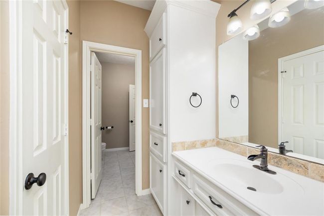 This secondary bathroom offers a clean, polished look with sleek white counters, custom cabinetry, and fresh paint completed in 2024. The elegant finishes create a bright and timeless space that’s perfect for both family and guests. | Image 38