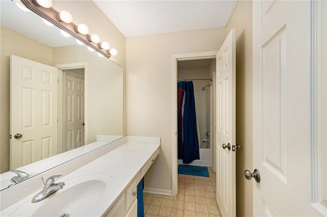 Full bathroom featuring vanity, shower / bath combination with curtain, baseboards, and tile patterned flooring | Image 24