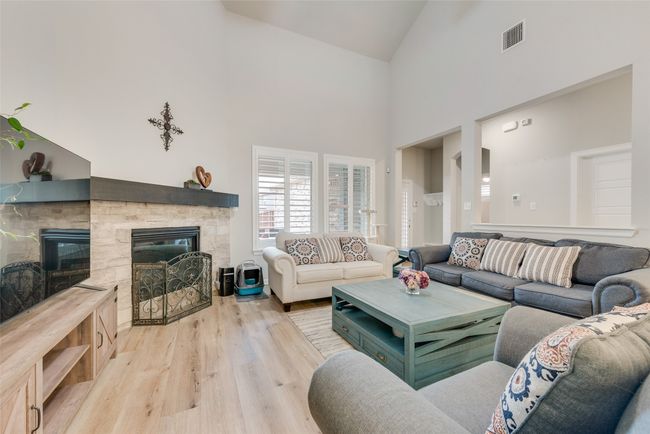 Living area with visible vents, high vaulted ceiling, light wood-style floors, and a fireplace | Image 5