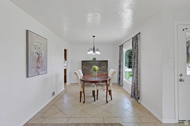 Dining area featuring a chandelier, light tile patterned floors, and baseboards | Image 9