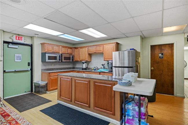 Kitchen featuring decorative backsplash, a paneled ceiling, appliances with stainless steel finishes, light wood-type flooring, and a center island | Image 18
