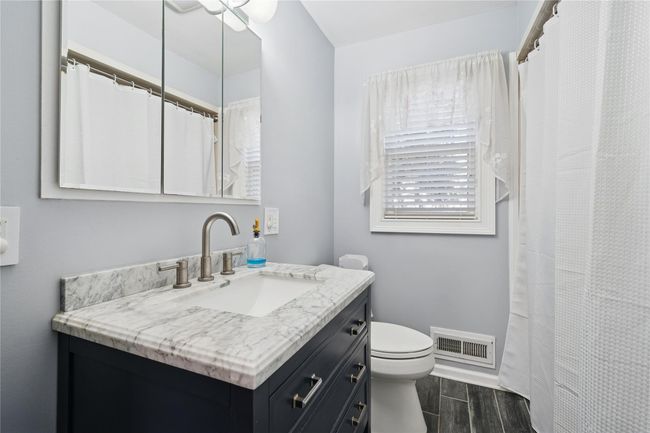Full bathroom featuring visible vents, baseboards, wood finish floors, toilet, and vanity | Image 33