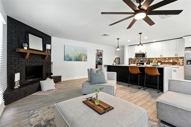 Spacious and inviting, this open-concept living area is ideal for entertaining—anchored by a bold black brick fireplace and oversized ceiling fan for added style and comfort. | Image 18