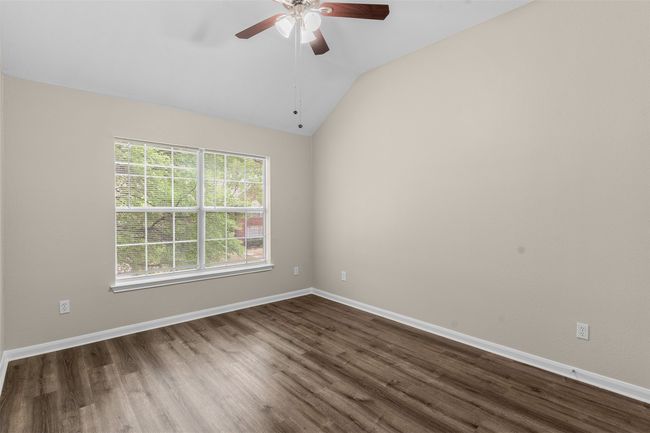 Empty room with dark wood-style flooring, baseboards, vaulted ceiling, and ceiling fan | Image 30