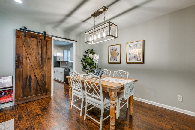 Dining space featuring dark wood-style floors, a barn door, and recessed lighting | Image 11