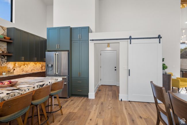 Kitchen featuring high end fridge, a high ceiling, a barn door, backsplash, and open shelves | Image 30