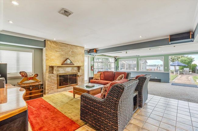 Carpeted living room with tile patterned flooring, plenty of natural light, a stone fireplace, ornamental molding, and recessed lighting | Image 25