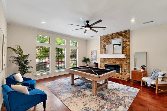 Recreation room with wood-type flooring, ceiling fan, crown molding, a fireplace, and pool table | Image 7