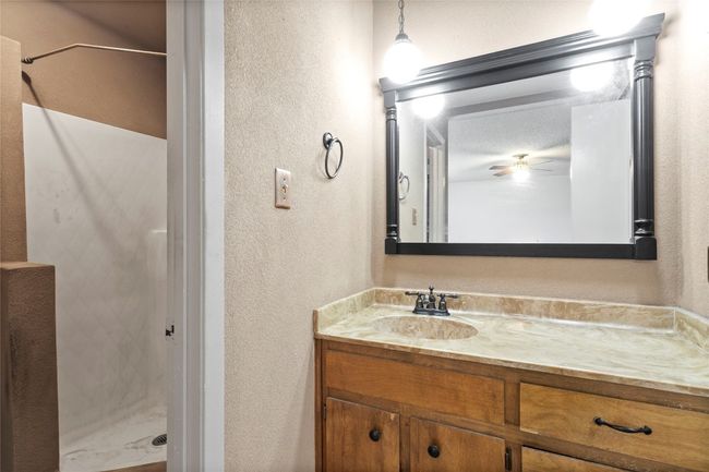 Bathroom featuring a textured wall, vanity, a shower stall, and ceiling fan | Image 27