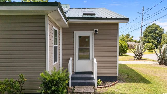 View of exterior entry with a lawn and a metal roof | Image 6