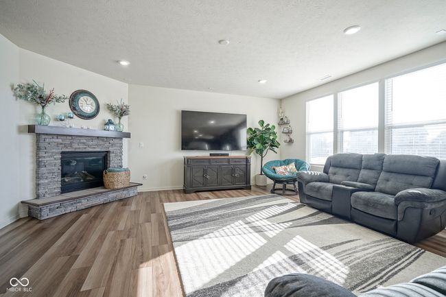 living room featuring light wood finished floors, a fireplace, a textured ceiling, baseboards, and recessed lighting | Image 14
