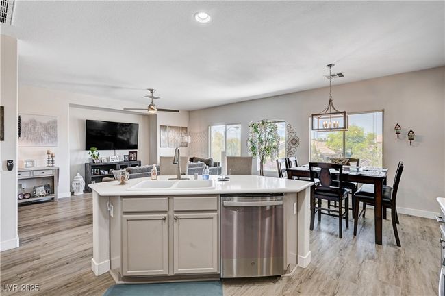 Kitchen with dishwasher, open floor plan, a kitchen island with sink, light countertops, and light wood finished floors | Image 4