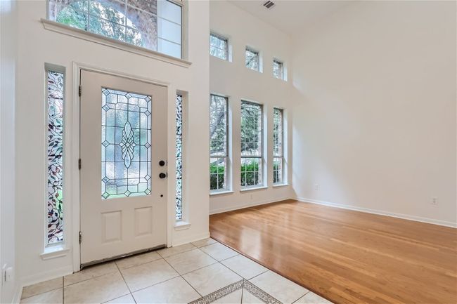 Entryway with a towering ceiling, light tile patterned floors, and baseboards | Image 5