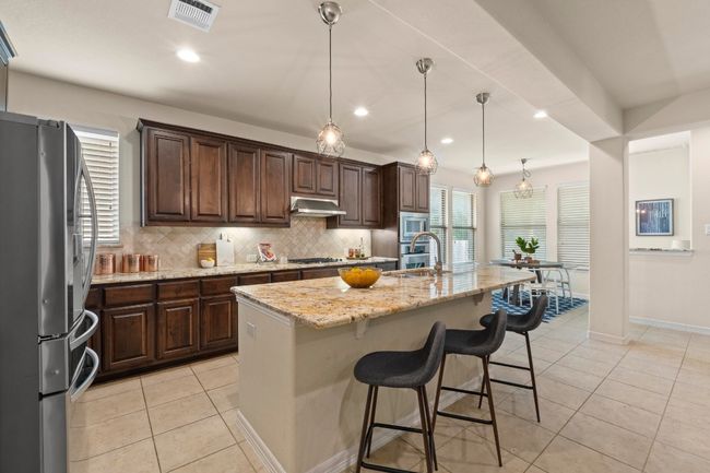 Kitchen featuring appliances with stainless steel finishes, healthy amount of natural light, decorative backsplash, light tile patterned floors, and recessed lighting | Image 10