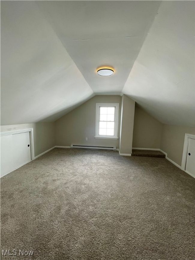 Additional living space featuring a baseboard radiator, lofted ceiling, and carpet | Image 25