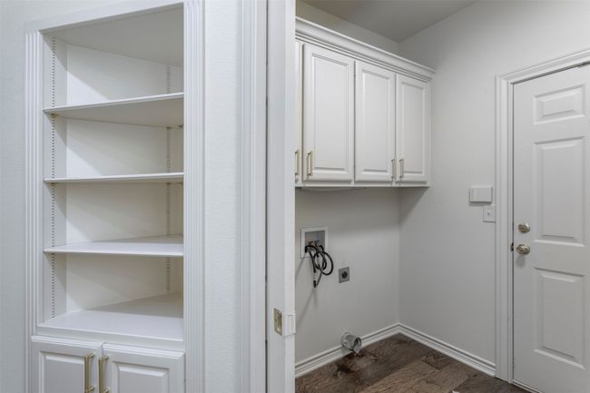 Laundry room with electric dryer hookup, hookup for a washing machine, dark wood finished floors, cabinet space, and baseboards | Image 25