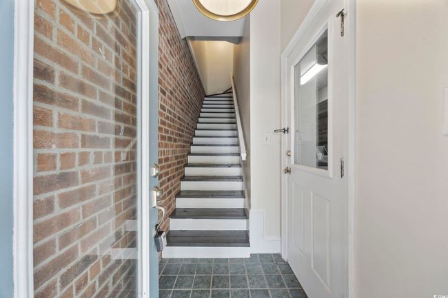 Stairway featuring brick wall and tile patterned floors | Image 8