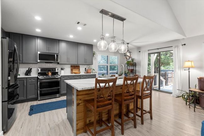 Kitchen featuring appliances with stainless steel finishes, gray cabinetry, light wood finished floors, backsplash, and healthy amount of natural light | Image 16