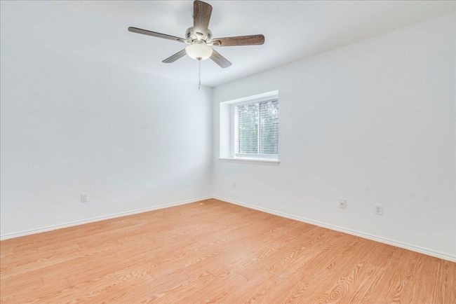 The guest bedroom welcomes you with a new ceiling fan, a walk-in closet, and warm wood laminate flooring. | Image 16