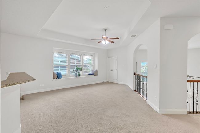 Empty room featuring arched walkways, a raised ceiling, a ceiling fan, and carpet flooring | Image 25
