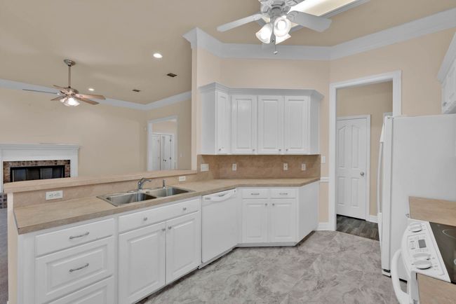 Kitchen with ceiling fan, white appliances, a peninsula, light countertops, and a fireplace | Image 11