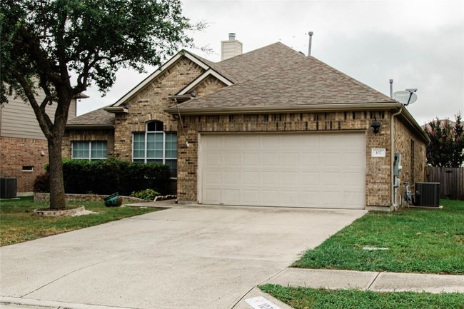 Traditional home featuring a garage, concrete driveway, roof with shingles, brick siding, and a chimney | Image 4