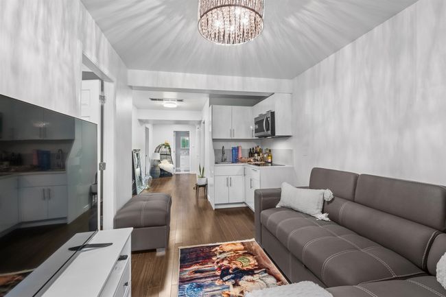 Living area with a bar, dark wood-type flooring, and a chandelier | Image 14