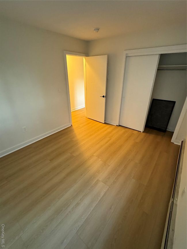 Unfurnished bedroom featuring wood finished floors, a closet, and a baseboard radiator | Image 9