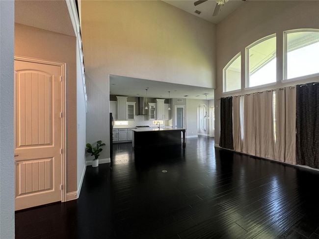 Living area with ceiling fan, dark wood finished floors, and a high ceiling | Image 6