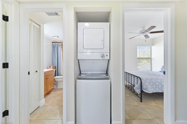 Clothes washing area featuring light tile patterned floors, stacked washer / drying machine, visible vents, and ceiling fan | Image 10