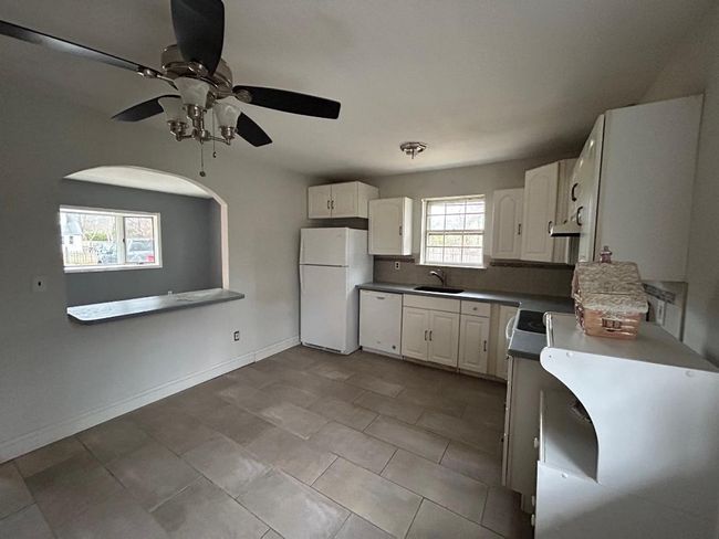 Kitchen with white appliances, white cabinets, backsplash, and sink | Image 10