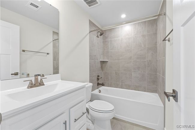 Bathroom with vanity, toilet, shower / tub combination, and visible vents | Image 13