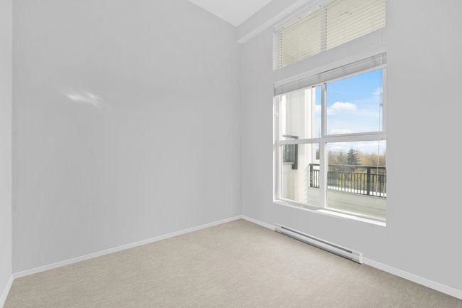 Spare room featuring baseboard heating, high vaulted ceiling, light carpet, and baseboards | Image 16
