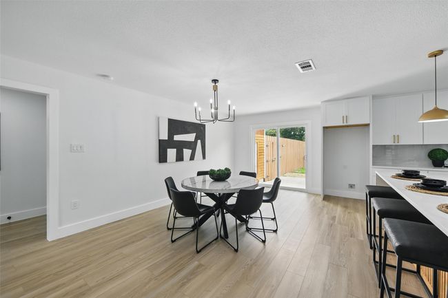 Dining space with a chandelier, light wood-style floors, baseboards, and a textured ceiling | Image 14