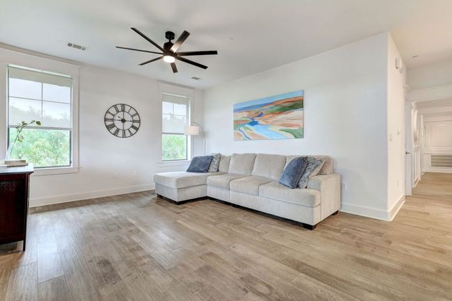 Living room with light wood-style flooring, a ceiling fan, plenty of natural light, and baseboards | Image 12
