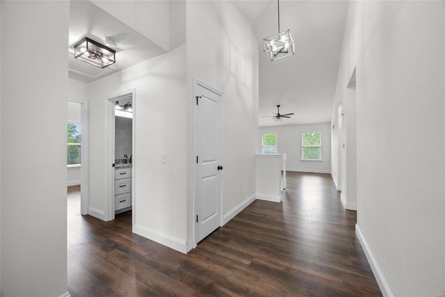 Hallway with an inviting chandelier, dark wood finished floors, and baseboards | Image 11