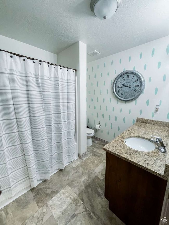 Full bath featuring wallpapered walls, vanity, toilet, a textured ceiling, and a shower with curtain | Image 6