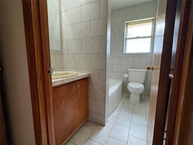 Unit B bathroom with tile flooring, walls and tub shower combo. | Image 6