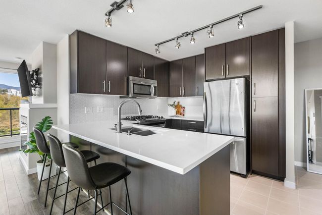 Kitchen featuring a peninsula, baseboards, stainless steel appliances, and a breakfast bar | Image 7