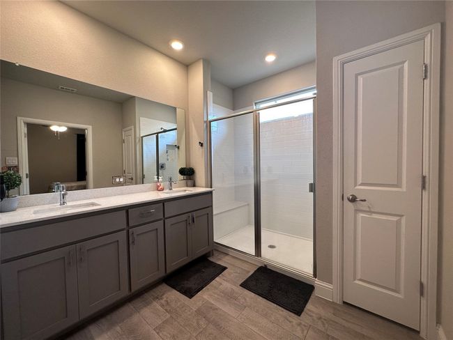 Full bath with double vanity, a stall shower, wood finished floors, and recessed lighting | Image 12