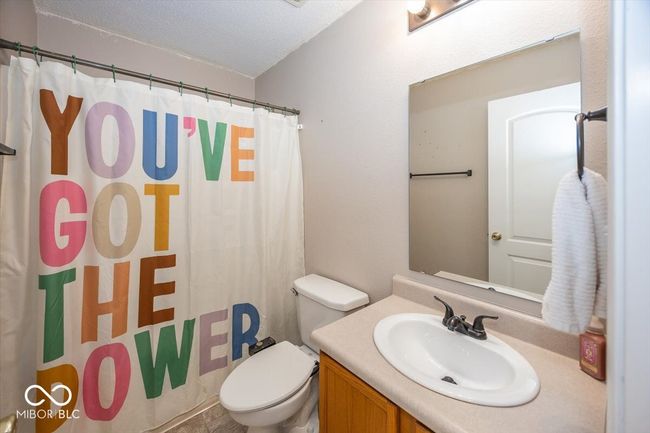 full bath with toilet, a shower with curtain, vanity, and a textured ceiling | Image 22