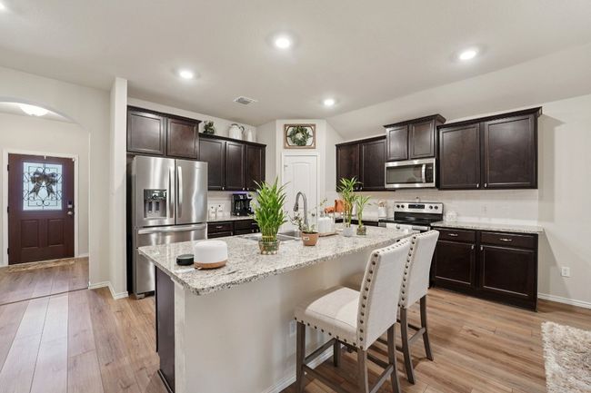 Kitchen featuring appliances with stainless steel finishes, backsplash, a breakfast bar area, dark brown cabinets, and recessed lighting | Image 12