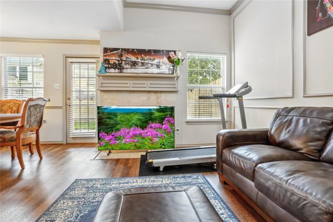 Living area featuring ornamental molding, wood finished floors, plenty of natural light, and a premium fireplace | Image 4