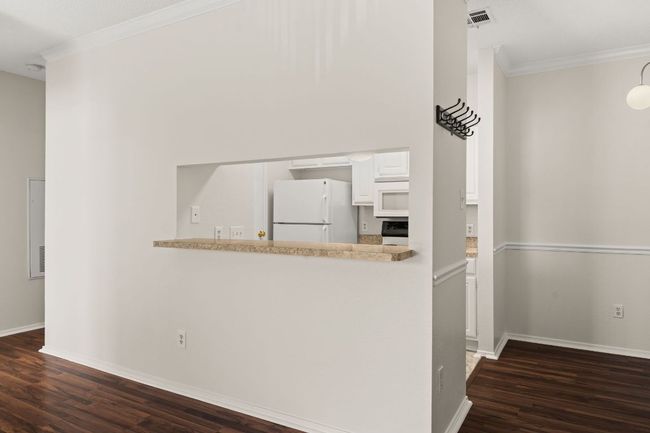 Kitchen featuring visible vents, dark wood-style floors, white cabinetry, white appliances, and crown molding | Image 17