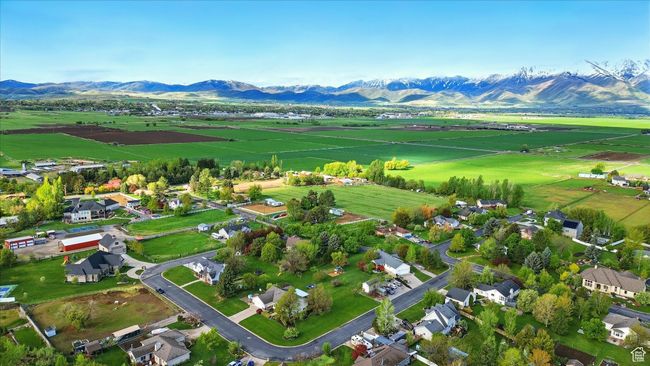 Aerial view of sparsely populated area with a mountain backdrop and rows of crops | Image 7