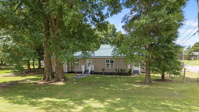 View of front of home with a metal roof, a front lawn, and entry steps | Image 11