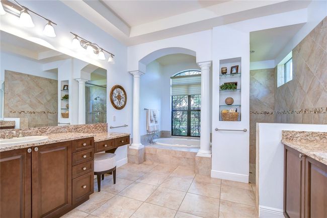 Featuring elegant columns and a serene garden view, the space is complemented by rich granite countertops and expansive dual vanities. | Image 21
