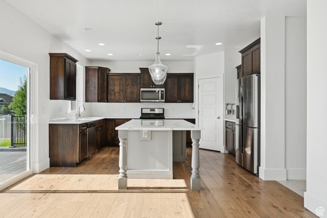 Kitchen featuring stainless steel appliances, a kitchen island, dark brown cabinets, decorative backsplash, and recessed lighting | Image 7