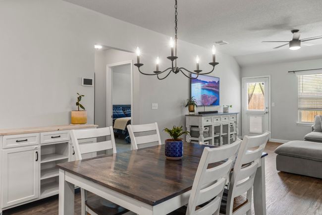 Dining space with dark wood-style flooring, a chandelier, and ceiling fan | Image 8