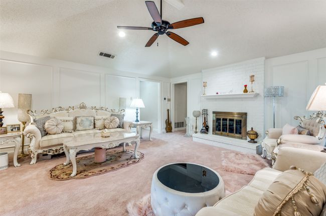 Living room featuring ceiling fan, carpet floors, a decorative wall, a fireplace, and lofted ceiling | Image 4